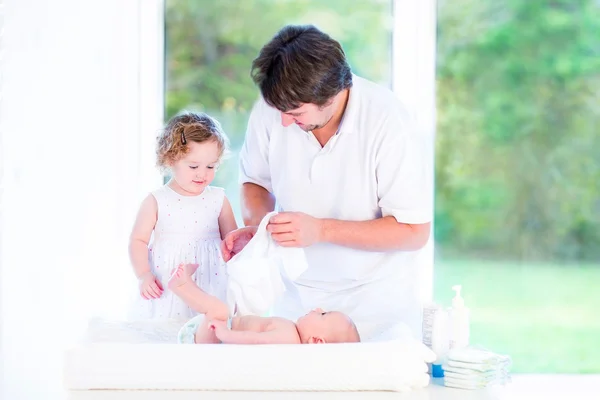 Girl helping her father to change a diaper of her brother — Stock Photo, Image