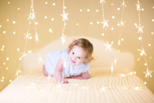 Adorable toddler girl playing on a bed — Stock Photo, Image