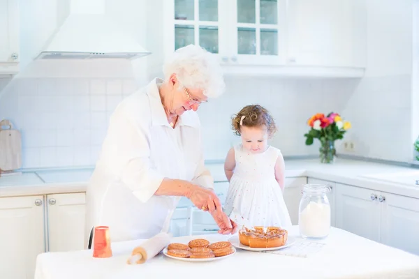 Großmutter backt mit ihrer kleinen Enkelin einen Apfelkuchen — Stockfoto