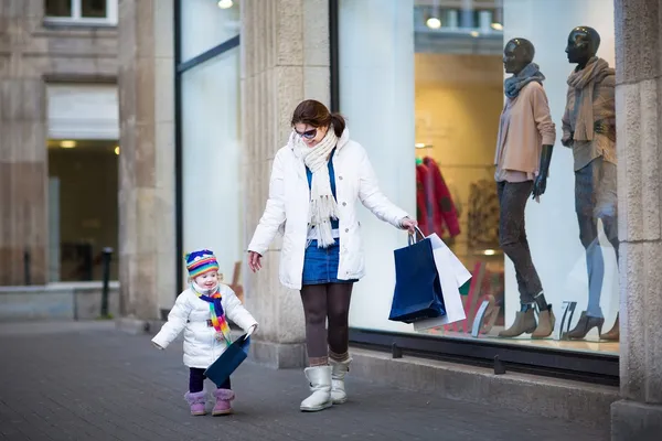 Mujer y su hija pequeña disfrutando de compras de venta de invierno — Foto de Stock