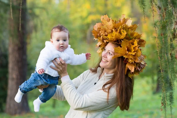 Mother holding a baby girl with a maple leaf wreath — Stock Photo, Image