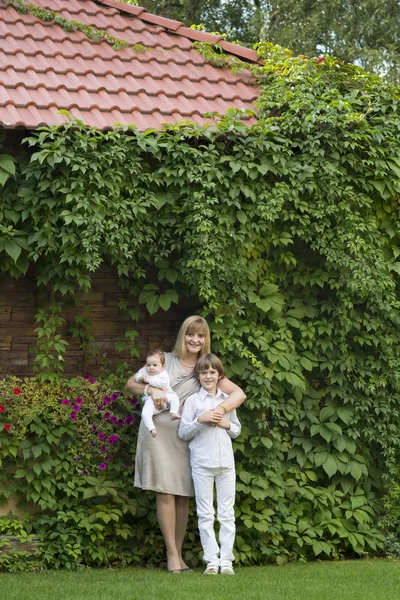 Beautiful lady in a formal dress with school boy and a baby — Stock Photo, Image