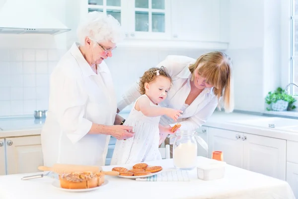 Süße lockige Kleinkind Mädchen backen einen Kuchen mit ihren Großmüttern — Stockfoto
