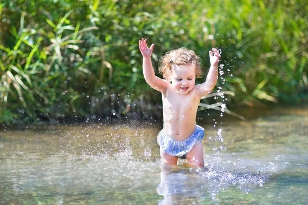 Baby girl splashing in a river — Stock Photo, Image