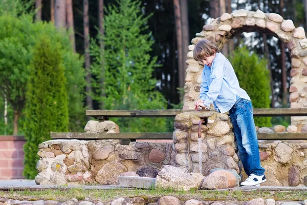 Boy playing with a water pump — Stock Photo, Image