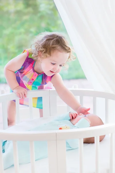 Toddler girl playing with newborn brother — Stock Photo, Image
