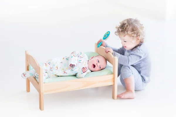 Peuter meisje spelen met houwen pasgeboren broertje — Stockfoto