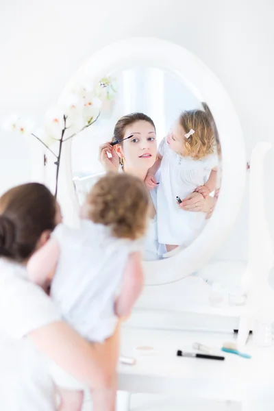 Woman applying make up and her toddler daughter watching — Stock Photo, Image