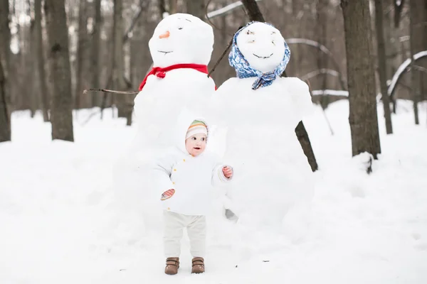 Bambino divertente accanto a un pupazzo di neve — Stockfoto