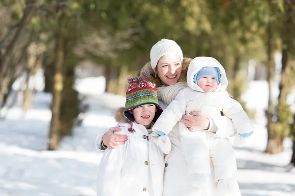 Moeder met twee kinderen lopen in een besneeuwde park — Stockfoto