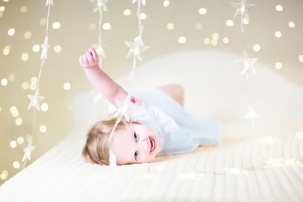 Kleinkind Mädchen spielt in einem weißen Bett — Stockfoto