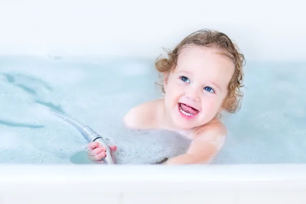 Baby girl with big blue eyes playing in a bath — Stock Photo, Image