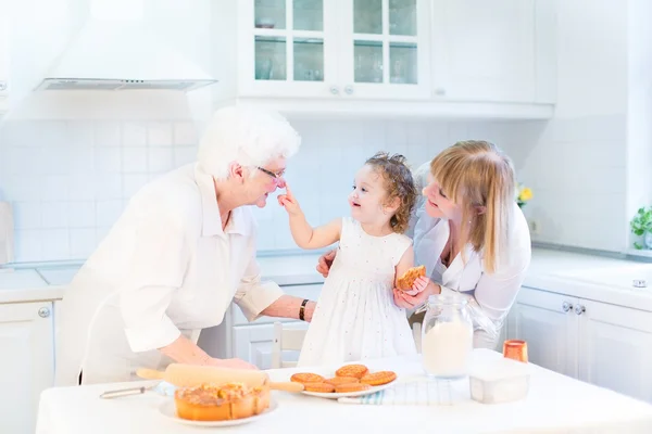 Toddler girl with her grandmothers in a kitchen