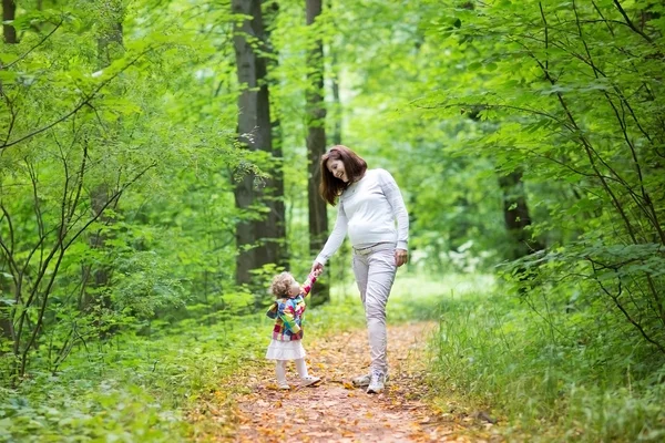 妊娠中の女性と彼女の赤ん坊の娘森を歩く — ストック写真