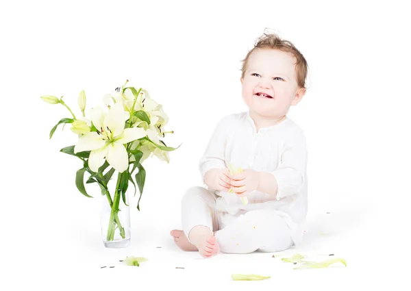 Baby playing with lily flowers — Stock Photo, Image