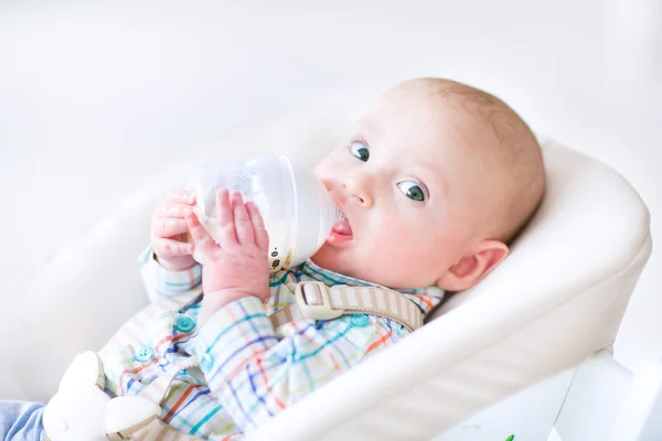 Мальчик, сидящий в кресле и пьющий молоко — стоковое фото