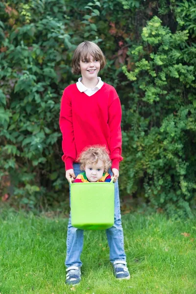 Brother and baby sister playing with a laudry basket — Stock Photo, Image