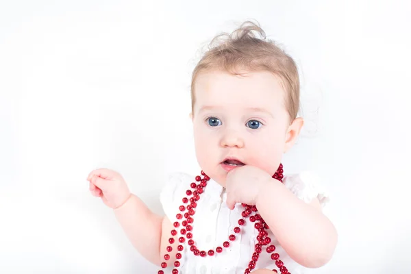 Cute baby girl playing with red necklace — Stock Photo, Image