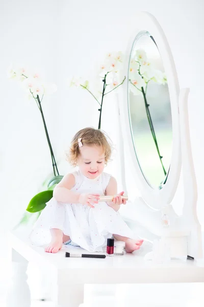 Маленькая девочка играет с макияжем и косметикой — стоковое фото