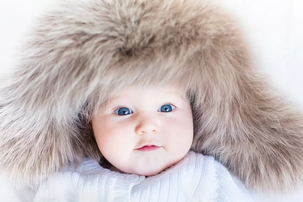 Menina bebê com grandes olhos azuis usando um enorme chapéu de inverno — Fotografia de Stock