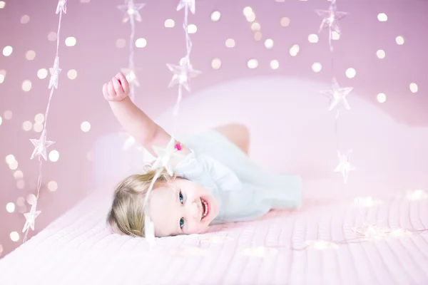 Menina da criança jogando em uma cama branca — Fotografia de Stock