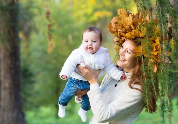Mother holding a baby girl with a maple leaf wreath — Stock Photo, Image