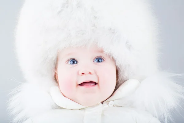 Funny laughing baby in a big white fur hat — Stock Photo, Image