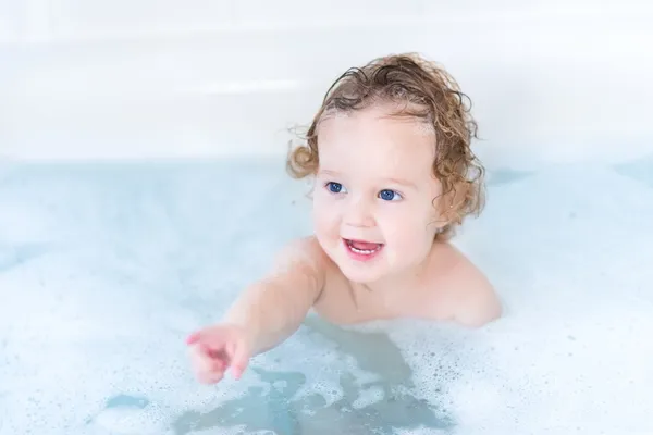 Bébé aux beaux yeux bleus et aux cheveux bouclés prenant son bain — Photo