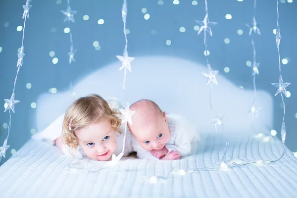 Bebê recém-nascido e irmã criança brincando em uma cama branca — Fotografia de Stock