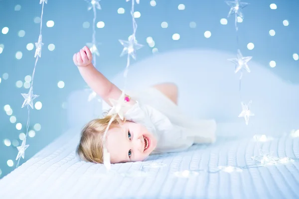 Menina da criança jogando em uma cama branca — Fotografia de Stock