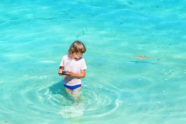 Chlapec hraje v oceánu s malý žralok — Stock fotografie