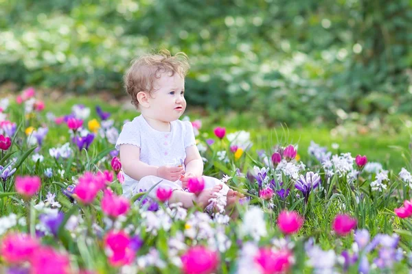 Baby sitting between spring flowers — Stock Photo, Image