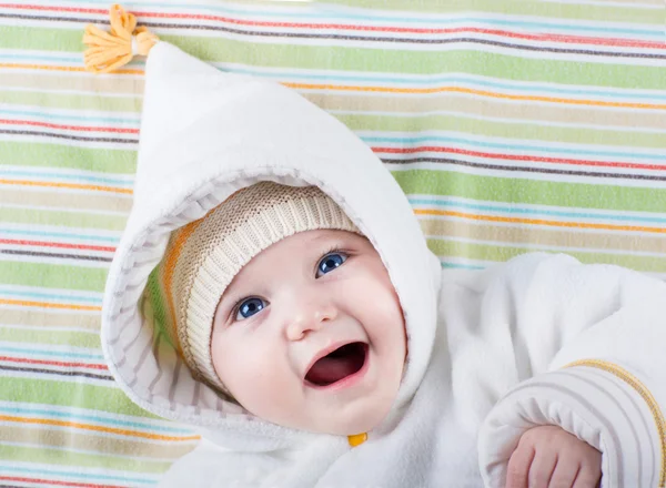 Cute funny laughing baby girl relaxing on a colorful blanket — Stock Photo, Image