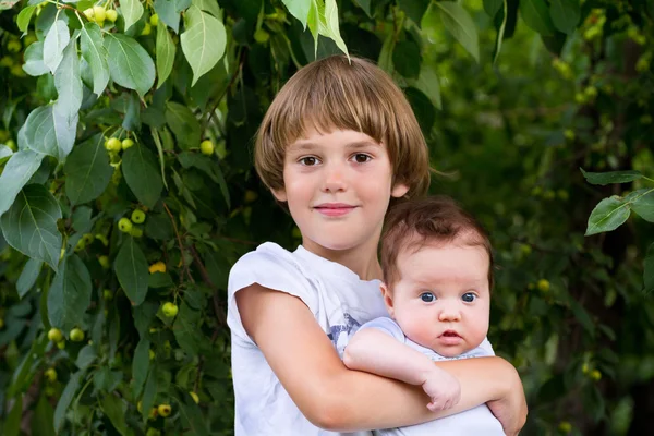 Lindo chico sosteniendo su hermanita — Foto de Stock