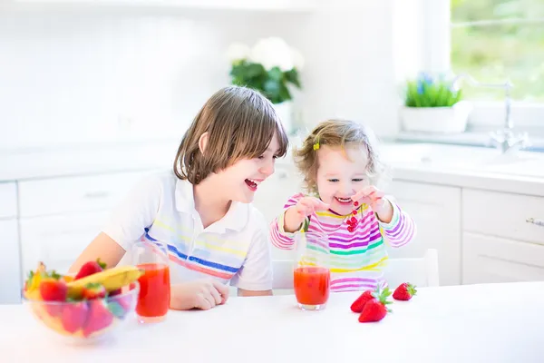 Мальчик-подросток и его сестра едят фрукты и хлопья с клубникой на завтрак — стоковое фото