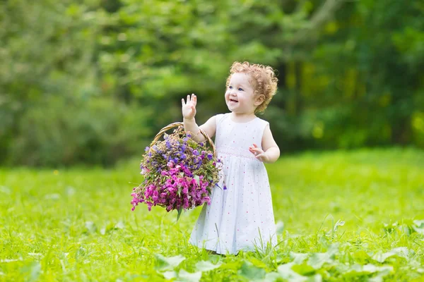 Baby girl with a basket of flowers — Stock Photo, Image