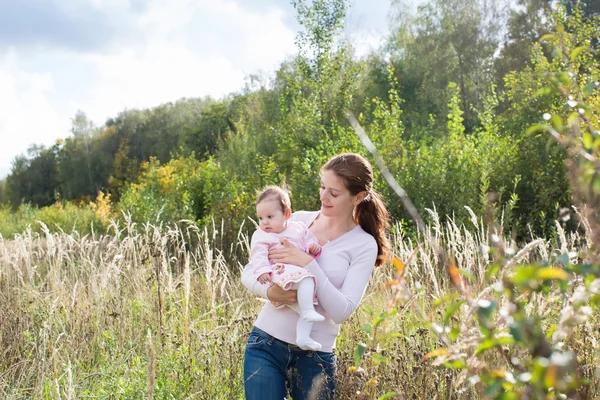 Moeder houdt van een meisje van de baby het dragen van een roze jurk — Stockfoto