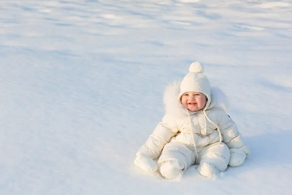 Funny baby playing with grass in a snow field — Stock Photo, Image