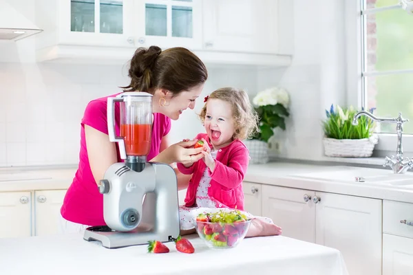 Irl und ihre junge mutter machen frischen erdbeersaft — Stockfoto