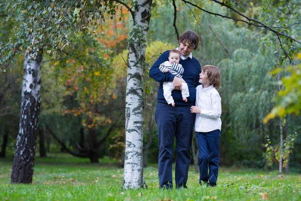 Padre y dos niños caminando en un bosque — Foto de Stock