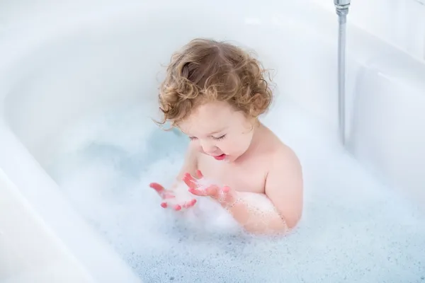 Bebê com belos olhos azuis e cabelos cacheados tomando banho — Fotografia de Stock