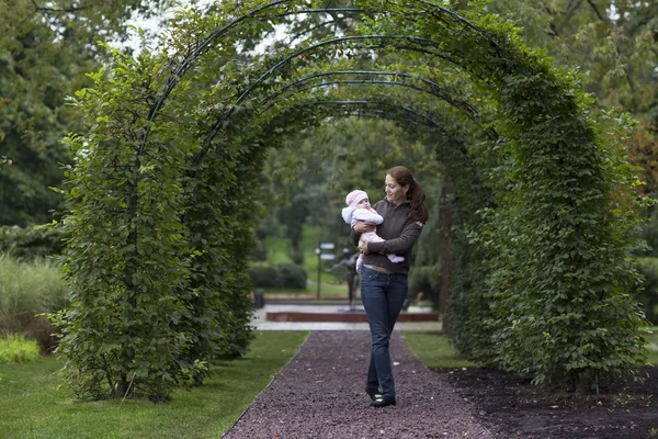 Moeder met pasgeboren onder een pergola — Stockfoto