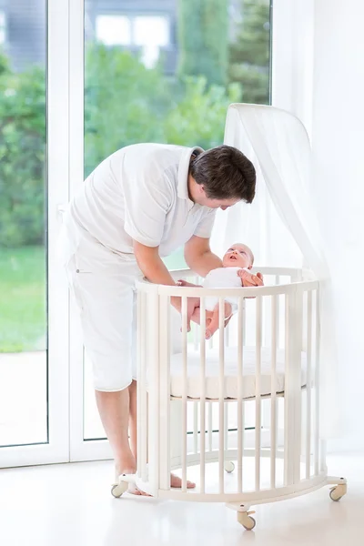 Junger lächelnder Vater legt sein neugeborenes Baby hin — Stockfoto