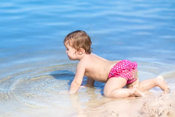 Bebé jugando en el agua en una playa — Foto de Stock