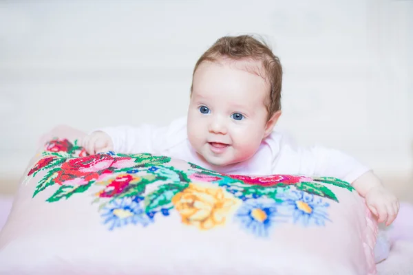 Baby flicka avkopplande på färgglada korset sytt kudden — Stockfoto