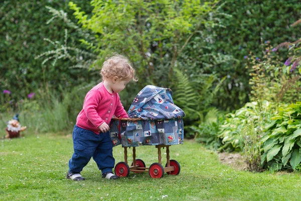 Baby girl playing with a vintage doll stroller — Stock Photo, Image