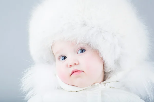 Büyük beyaz kürk şapka içinde komik gülen bebek — Stok fotoğraf