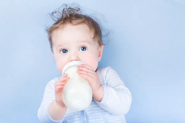 Маленька дитина з великими блакитними очима п'є молоко Ліцензійні Стокові Фото