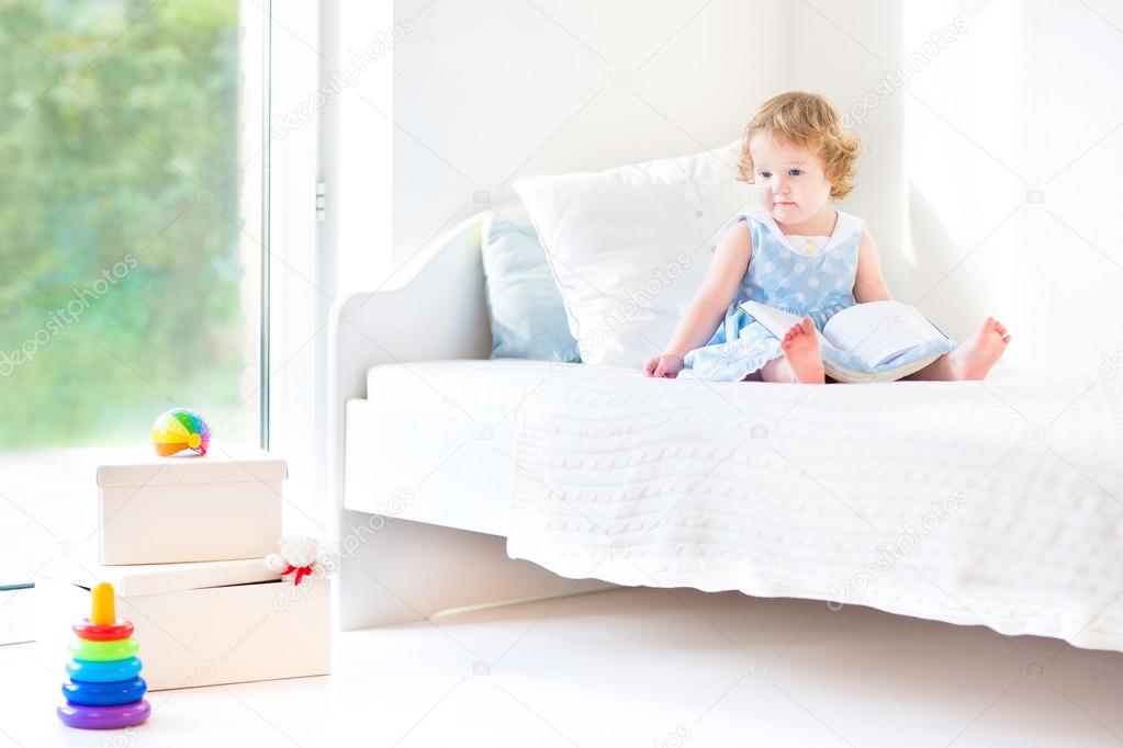 Toddler girl sitting on a white bed