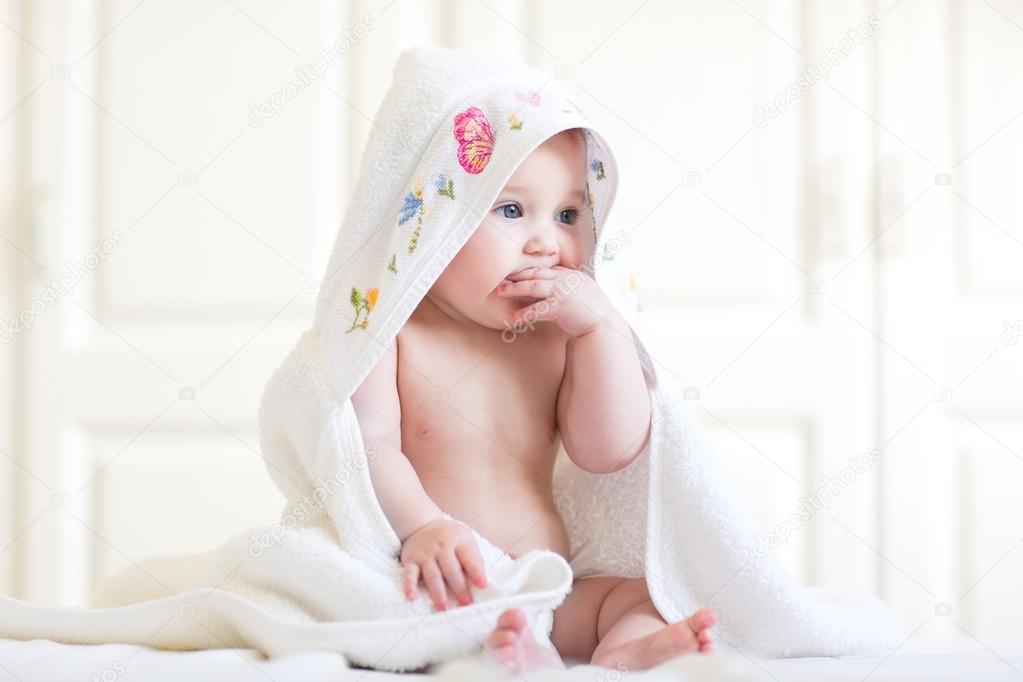 Baby girl sitting under a hooded towel after bath